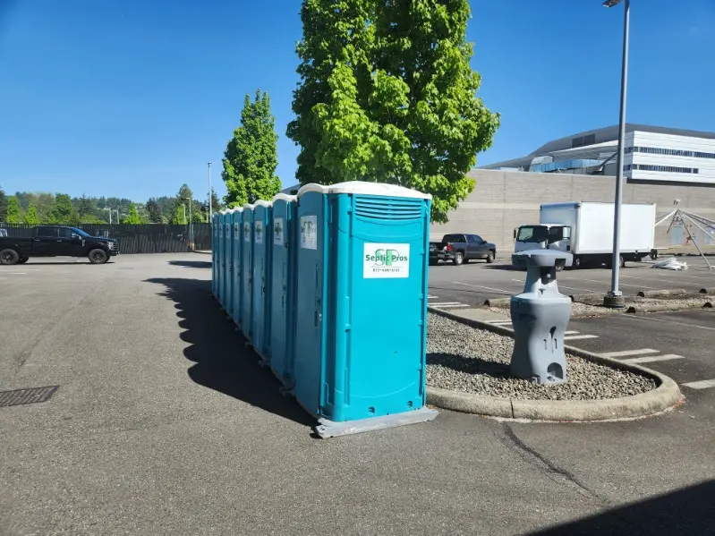 Portable toilets and a handwashing station staged in a job-site parking lot
