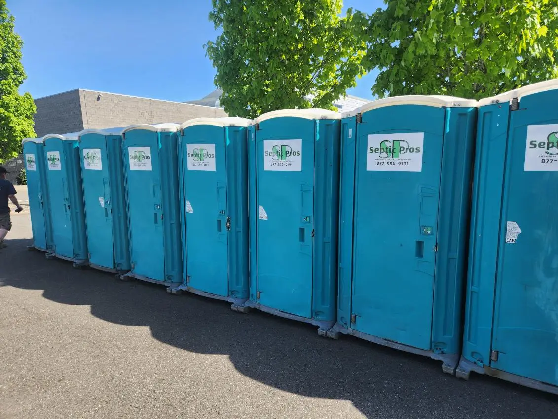 A long row of Septic Pros portable toilets and handwashing stations set up for an event
